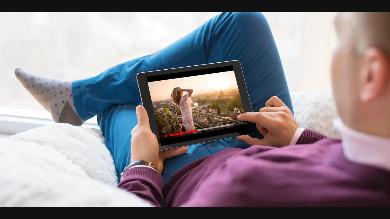 Person reclining and holding a tablet sideways to watch a video