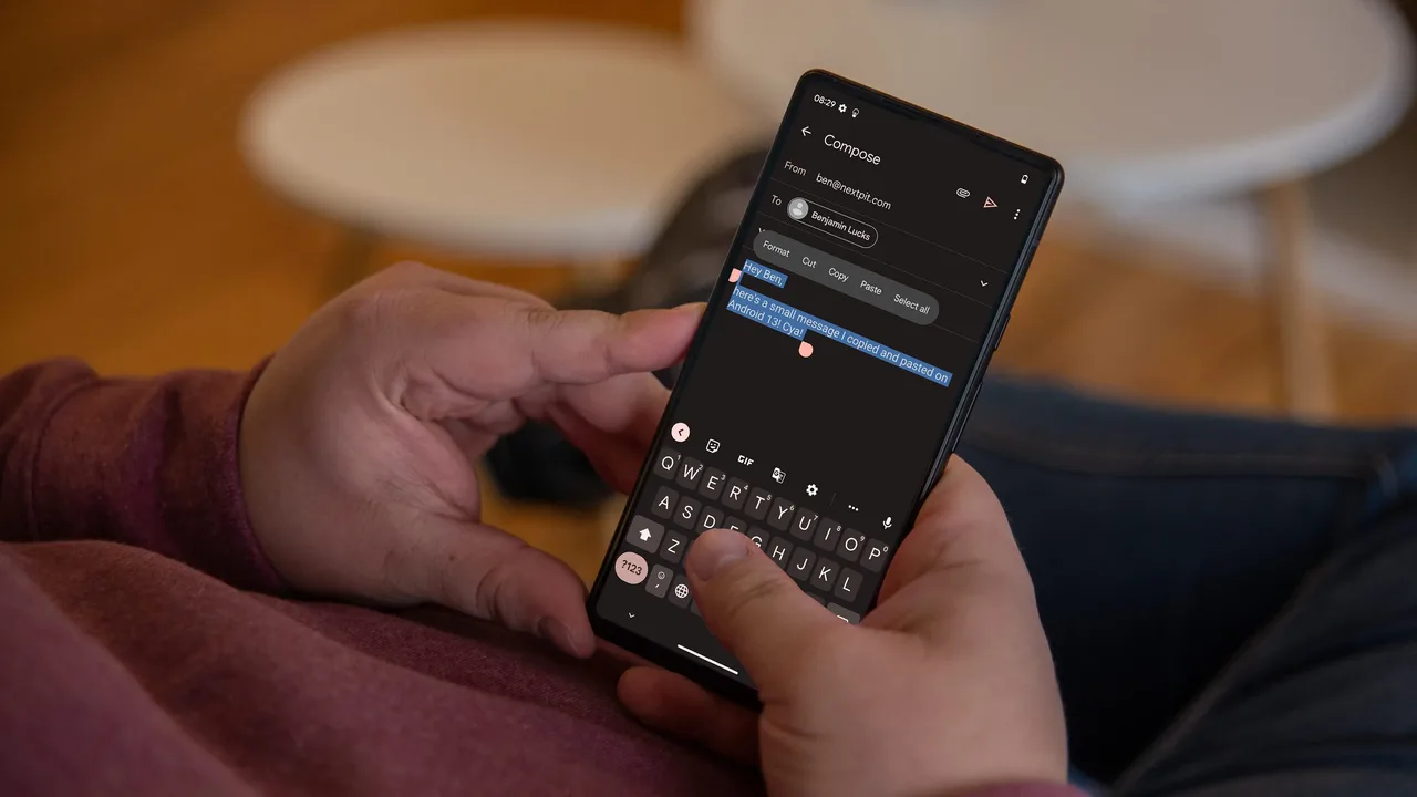 Hands holding a phone showing a Cut, Copy and Paste menu over selected text