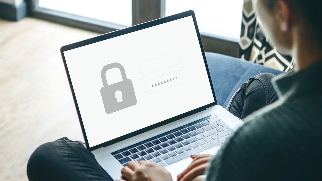 Person using a laptop showing a padlock and login fields on screen