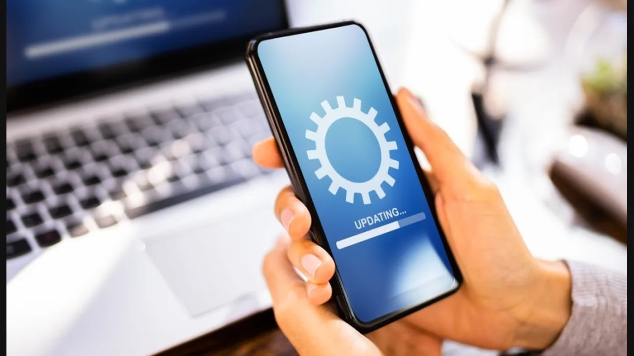Hands holding a phone showing an updating progress bar with a gear icon